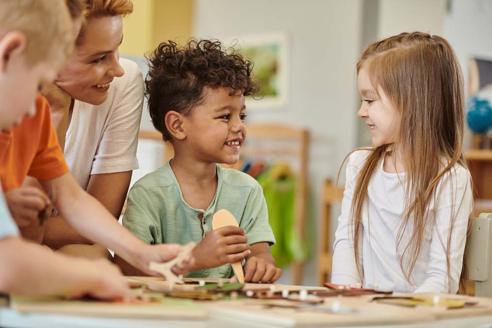 cheerful multiethnic kids playing near teacher during lesson in montessori school